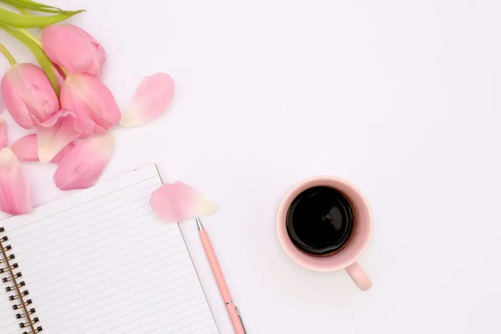 journal with pink tulips and cup of coffee on a table