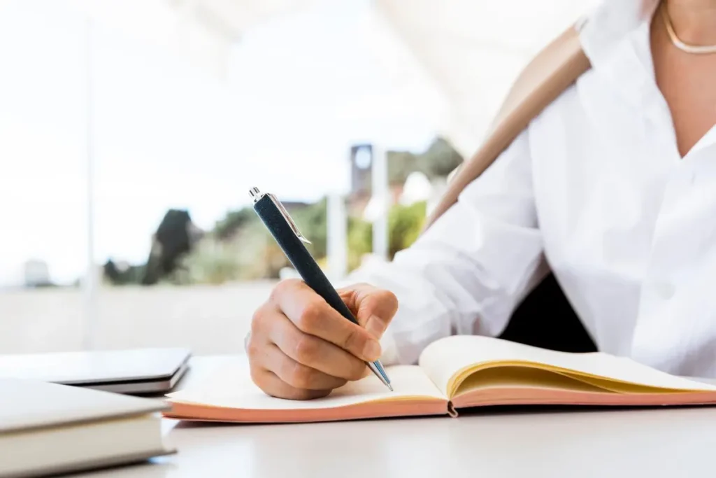 lady wearing white shirt writing in a journal