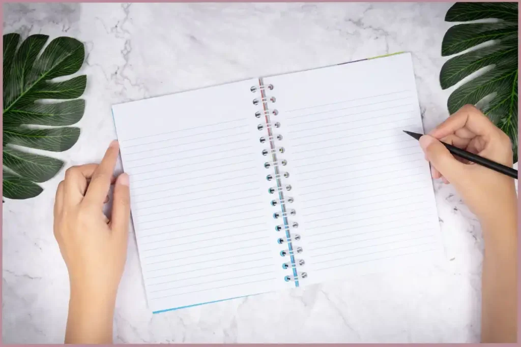 lady holding a pen poised to write in a blank journal