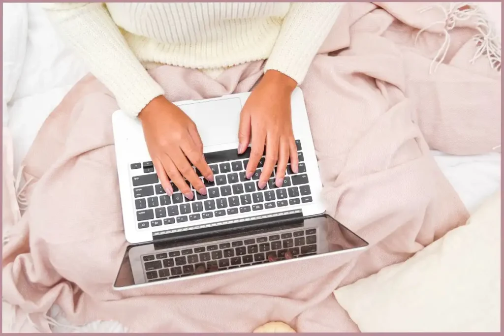 lady sitting on a bed working on a laptop - creative self care ideas for empty nesters