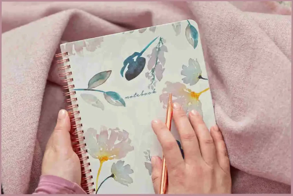 lady holding a notebook and golden pen - creative self care ideas for empty nesters